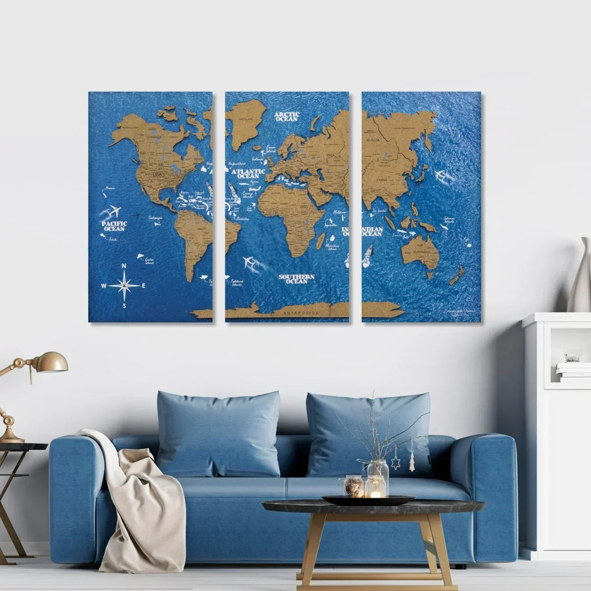 Dreiteiliges Wandbild mit Weltkarte auf blauem Hintergrund über einem blauen Sofa