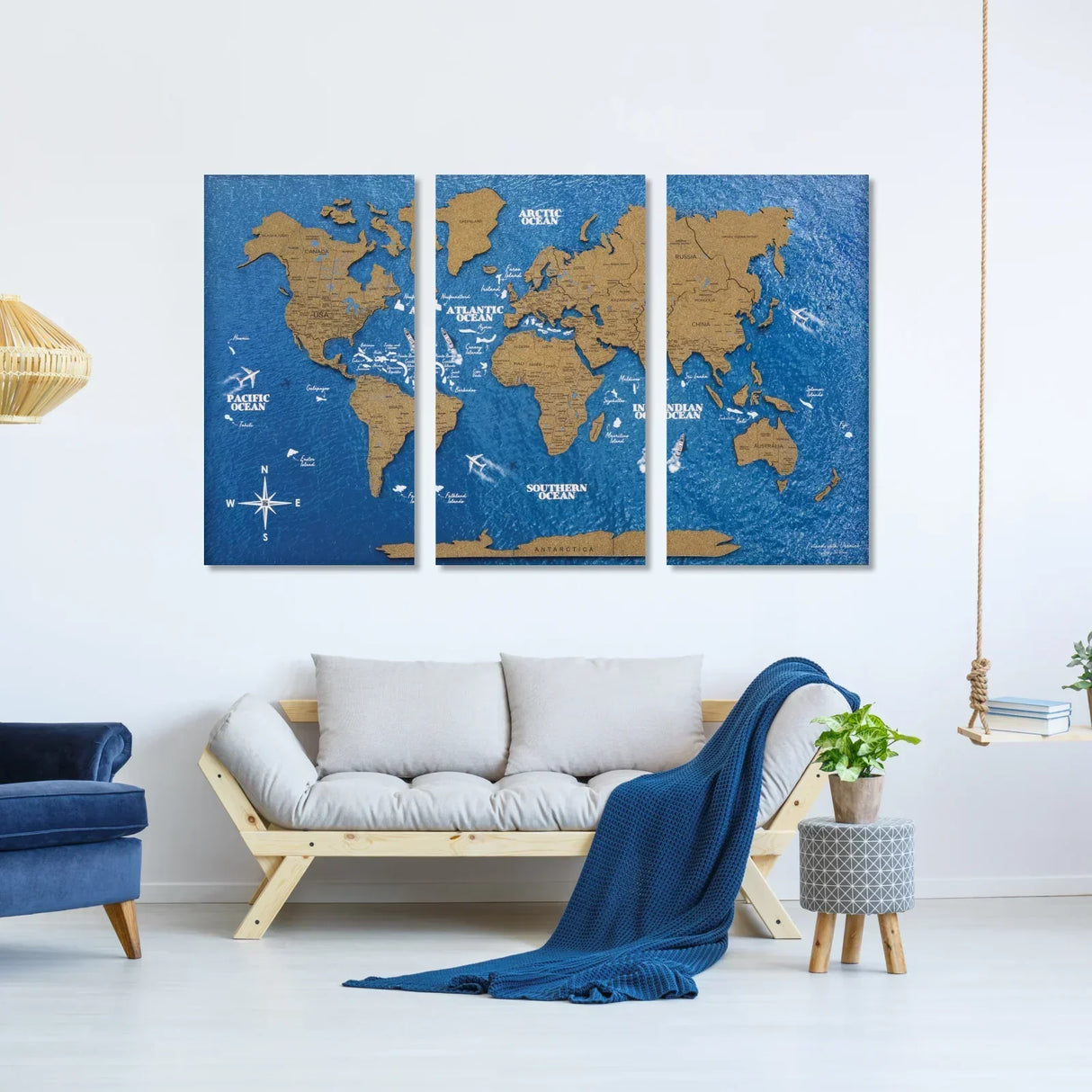 Dreiteiliges Wandbild mit Weltkarte aus Holz auf blauem Hintergrund über einem Sofa