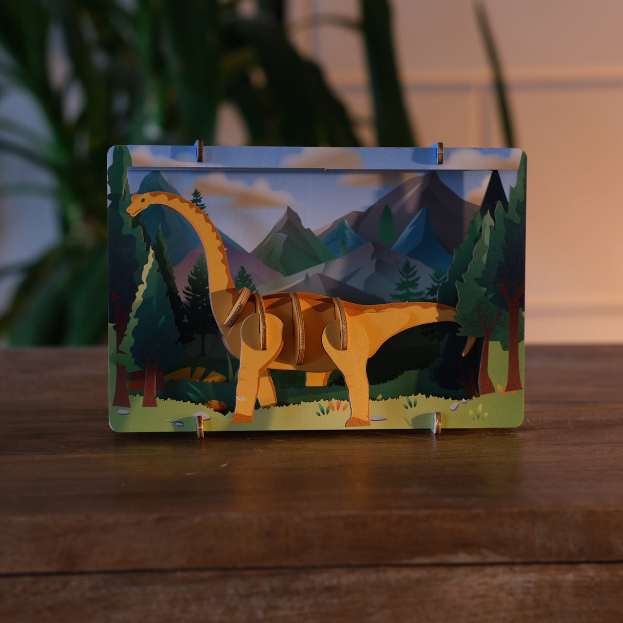 3D Holzmodell eines Dinosauriers vor einer illustrierten Berglandschaft