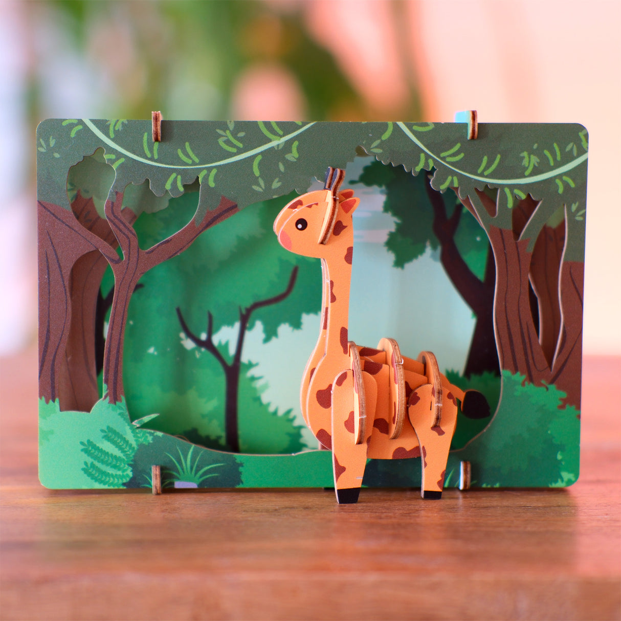Giraffenfigur aus Pappe vor einem Waldhintergrund