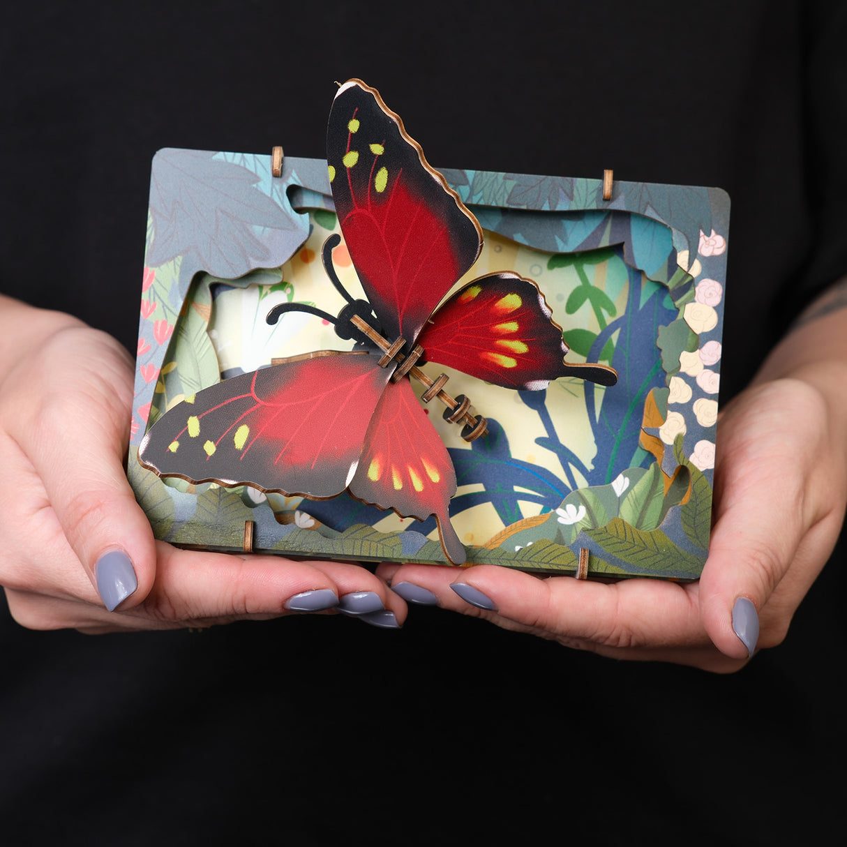 Holzschichtbild mit rotem Schmetterling in den Händen gehalten