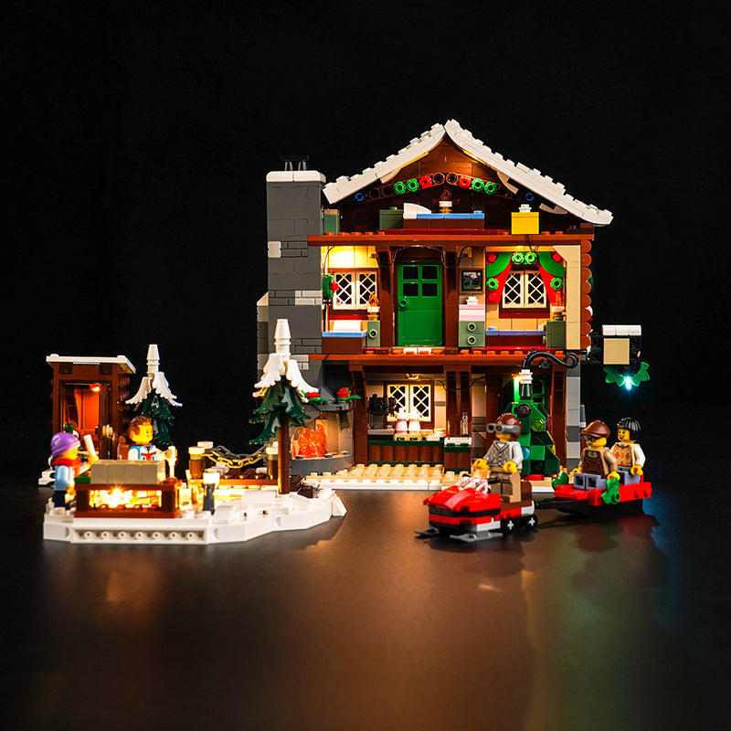 Beleuchtetes Lego Winterhaus mit Minifiguren und Schneemobil vor schwarzem Hintergrund