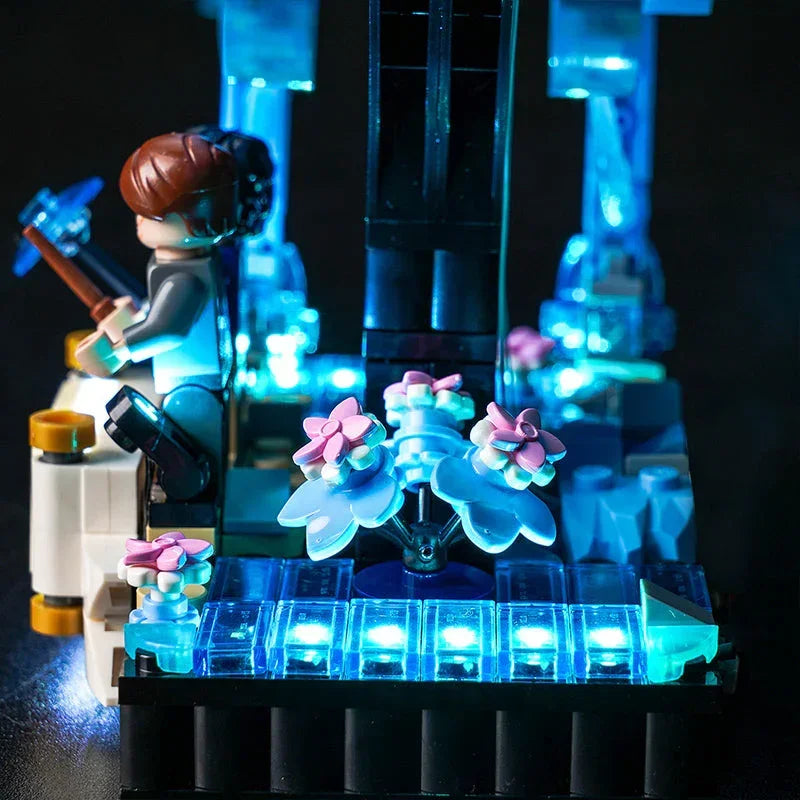 Beleuchtetes Lego Set mit Minifigur und blauen Blumen vor schwarzem Hintergrund
