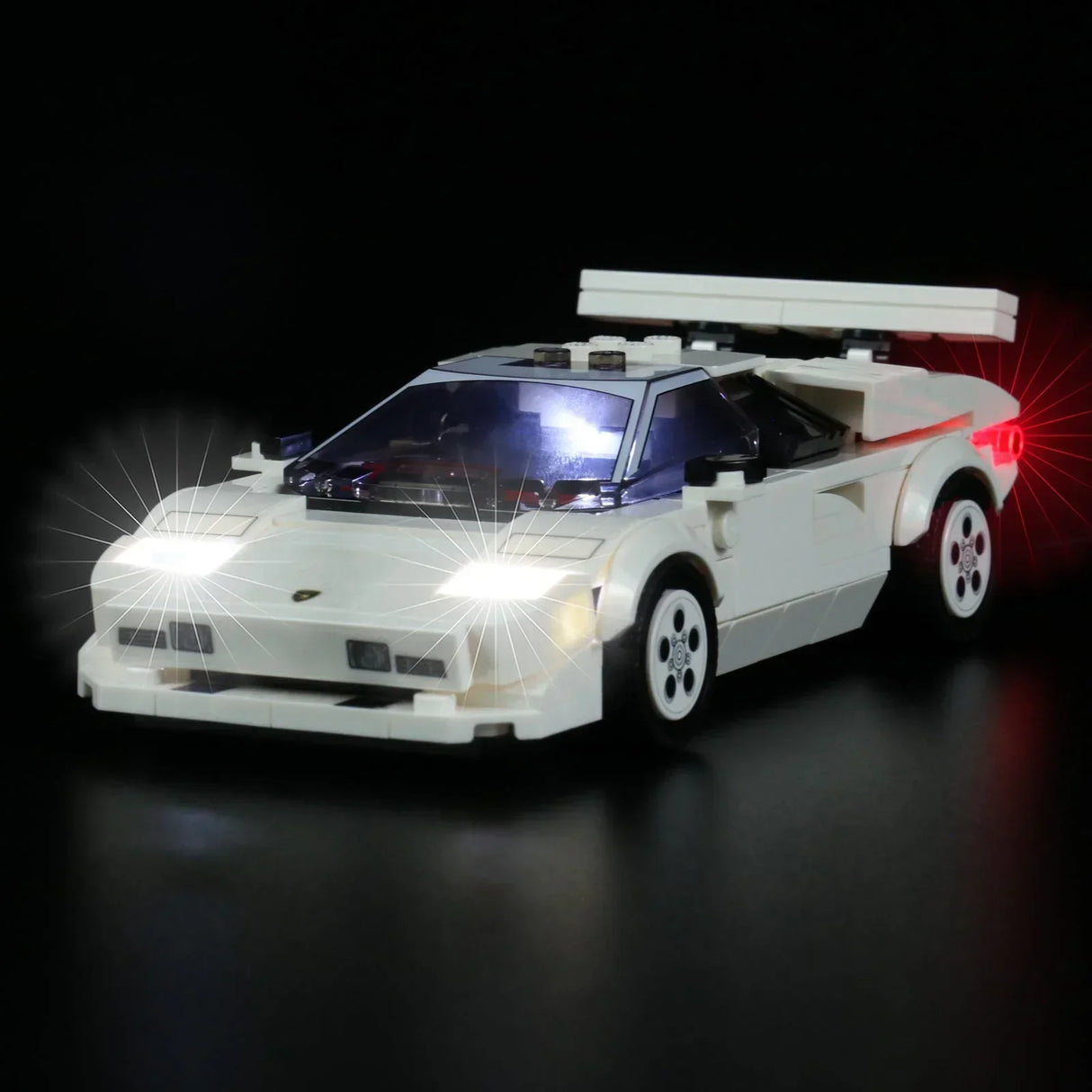 Weißes Lego Modellauto mit eingeschalteter LED Beleuchtung vor schwarzem Hintergrund