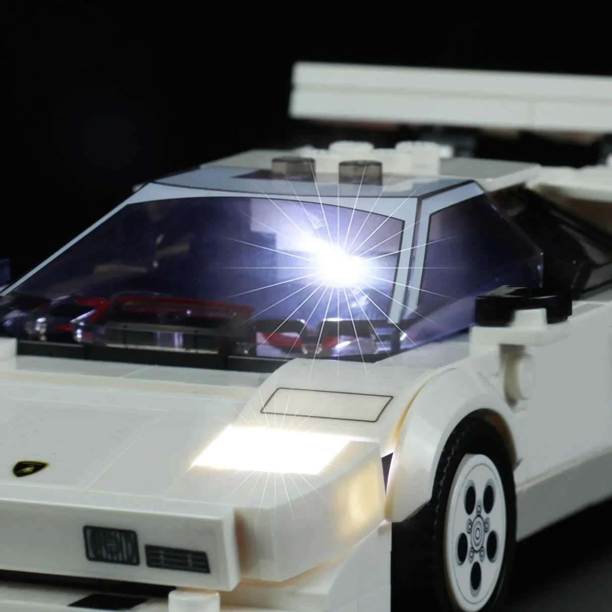 Weißes Modellauto aus Klemmbausteinen mit eingeschalteter LED Beleuchtung