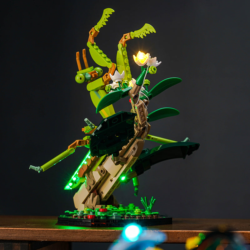 Beleuchtetes Lego Modell einer Gottesanbeterin auf einem Ast mit Blumen