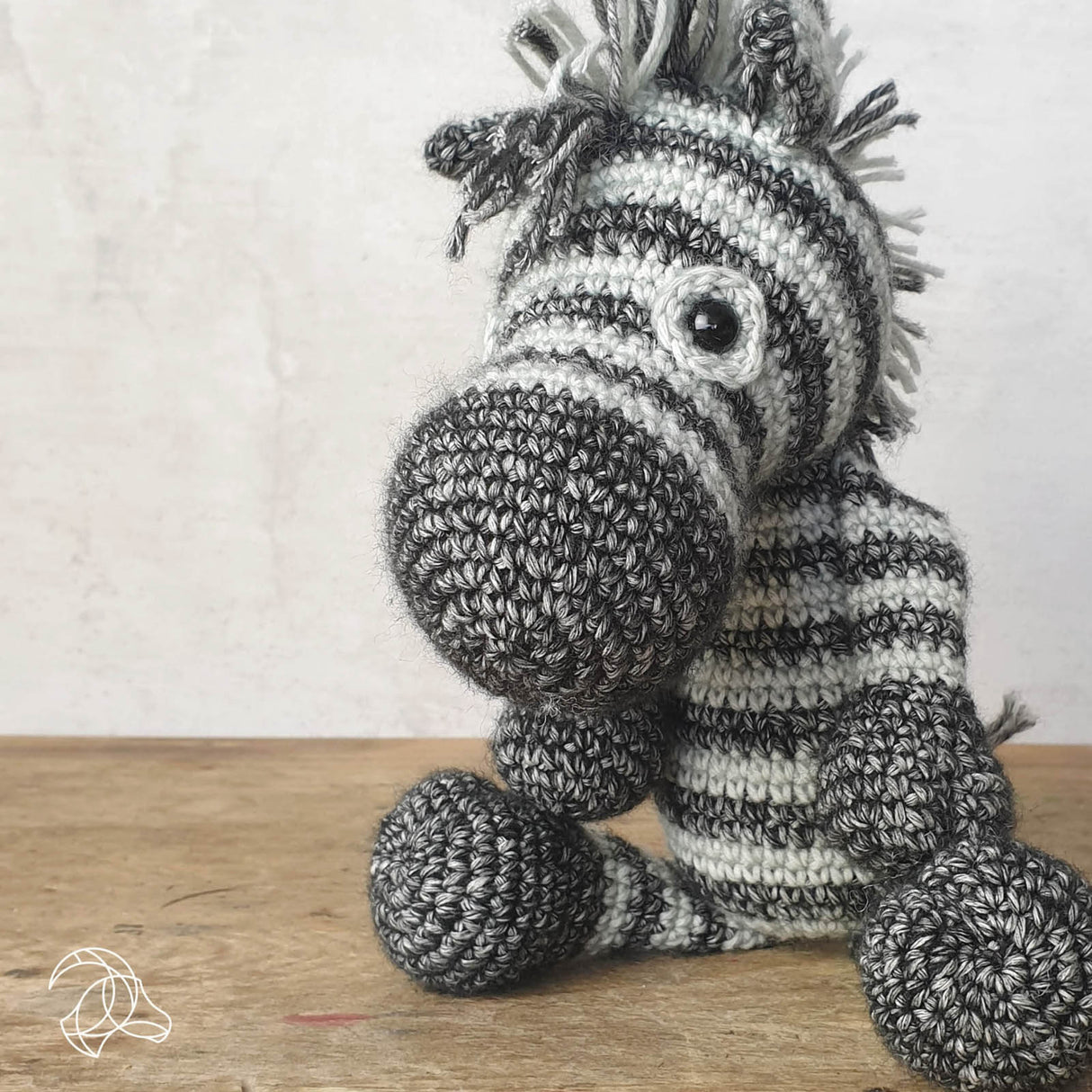 Gehäkeltes Zebra Kuscheltier in schwarz und weiß auf einem Holztisch