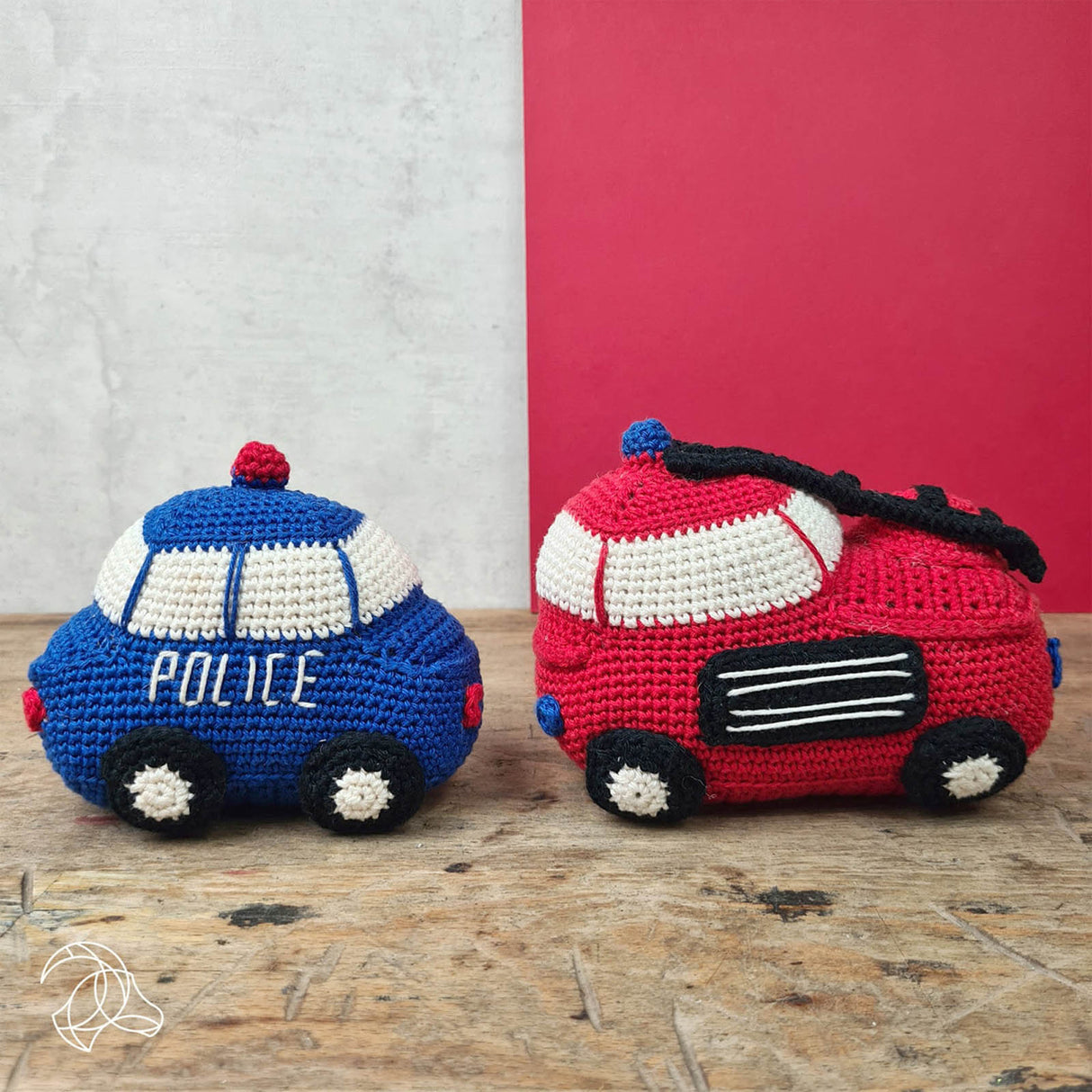 Gehäkeltes Polizeiauto und Feuerwehrauto als Spielzeug auf einem Holztisch