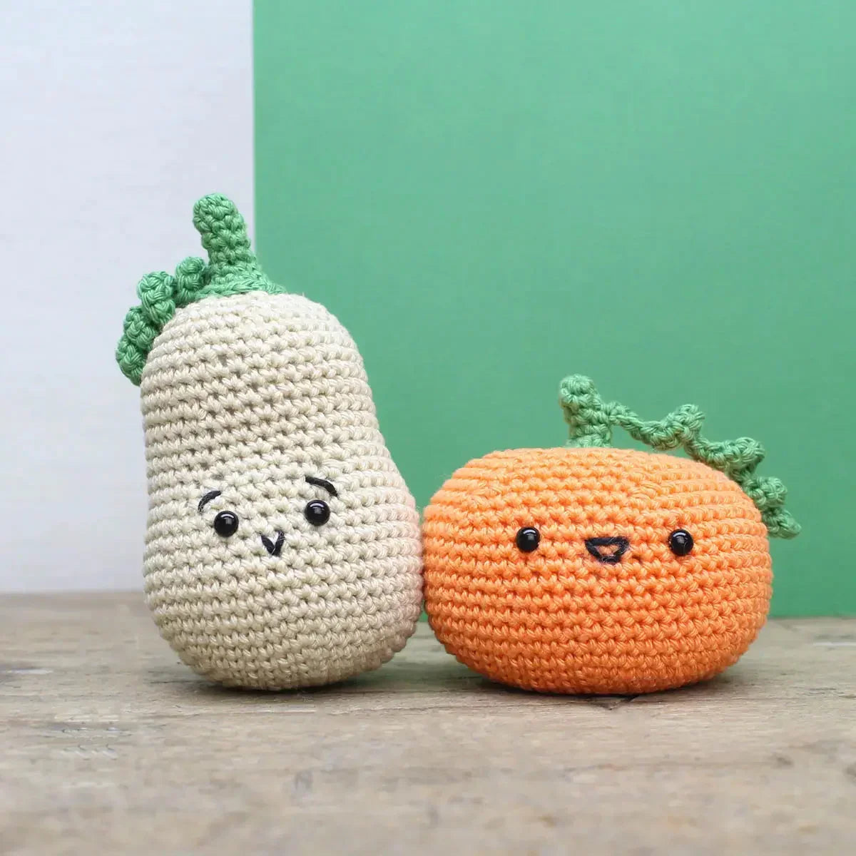 Zwei gehäkelte Figuren in Form einer hellen Birne und eines orangefarbenen Kürbisses mit aufgestickten Gesichtern