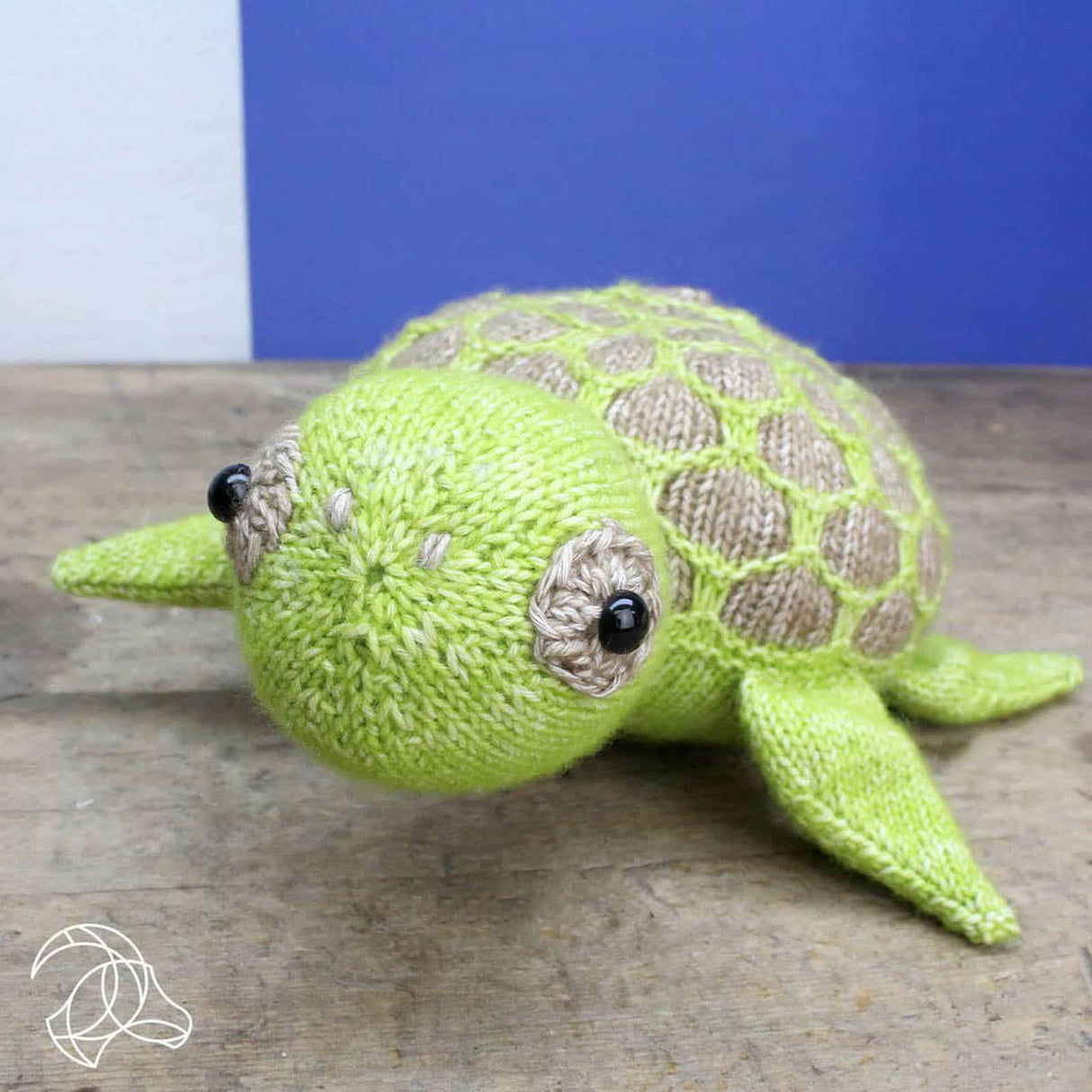 Gestrickte grüne Schildkröte als Kuscheltier auf einem Holztisch