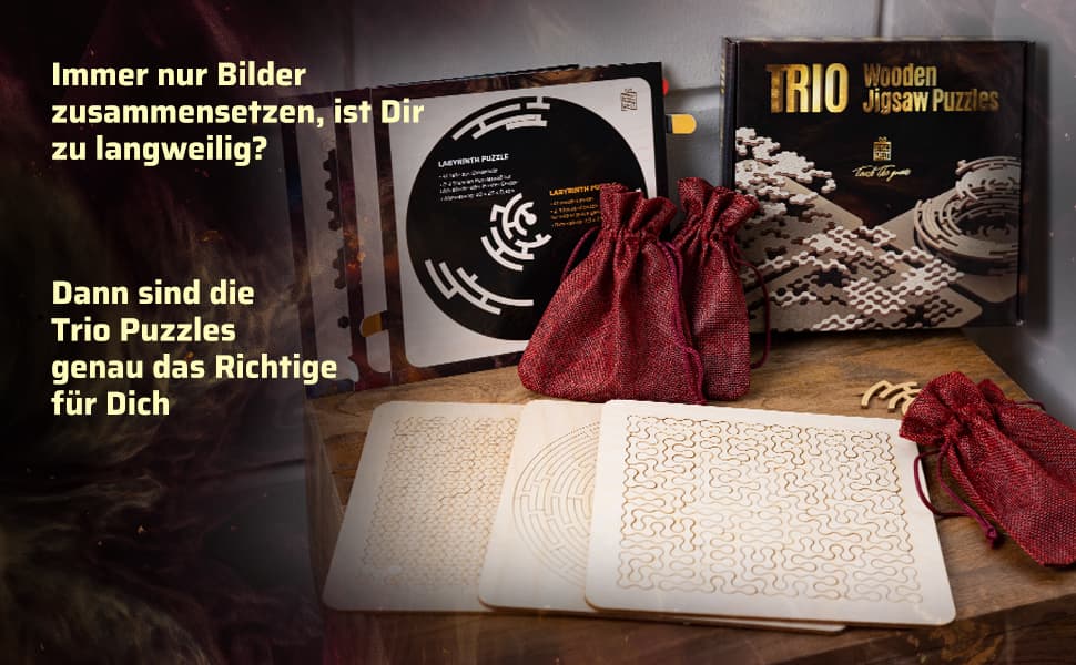 Produktübersicht des Wooden Trio Sets mit drei Holzplatten, roten Stoffbeuteln und der schwarzen Spielebox auf einer Holzoberfläche.