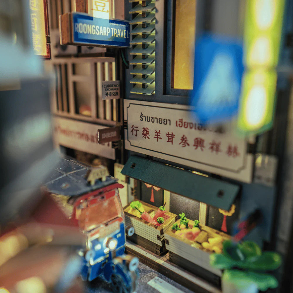 Miniatur-Straßenszene mit Tuk-Tuk, Geschäften und Leuchtreklamen