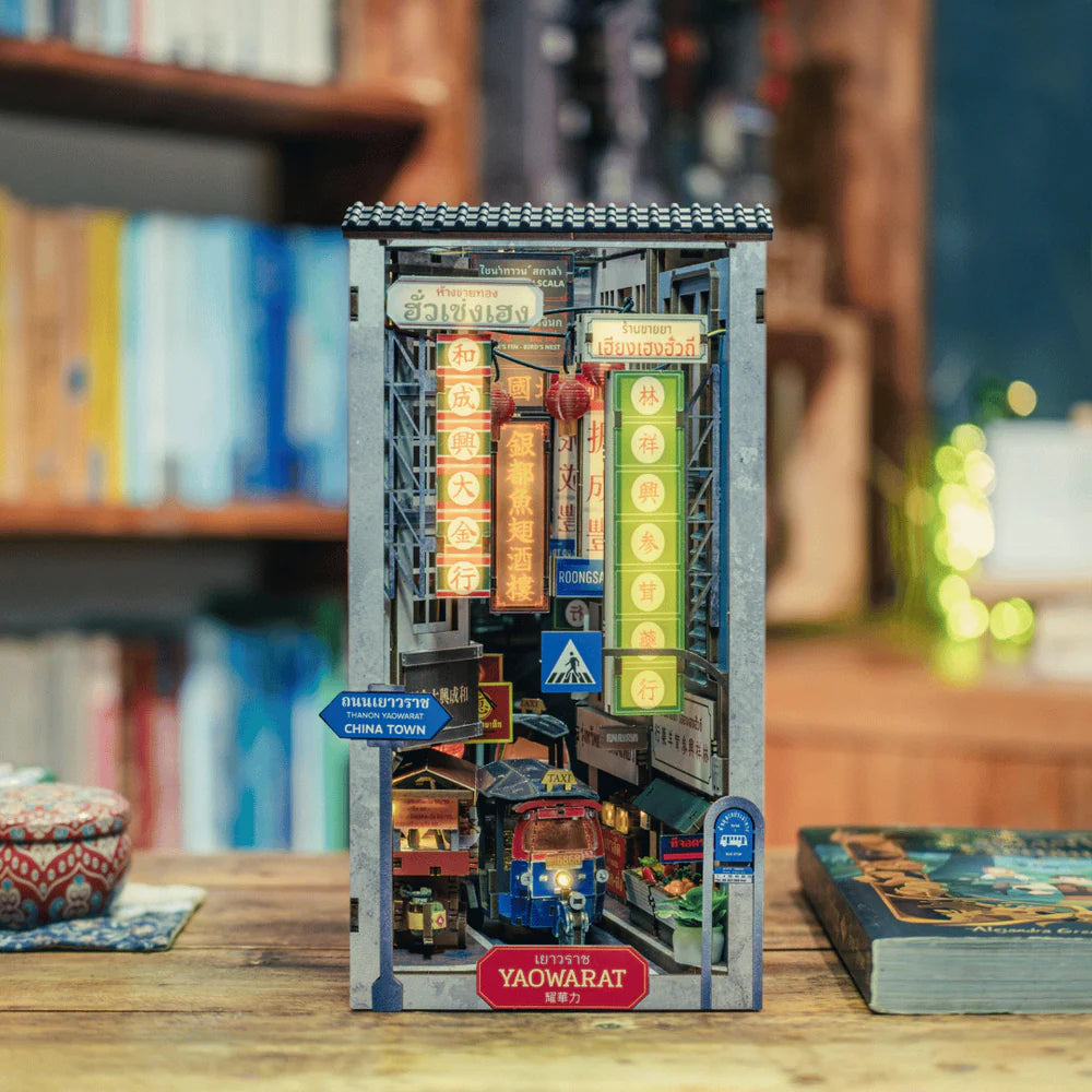 Miniatur-Diorama einer belebten Straße in Chinatown mit Tuk-Tuk und Leuchtreklamen