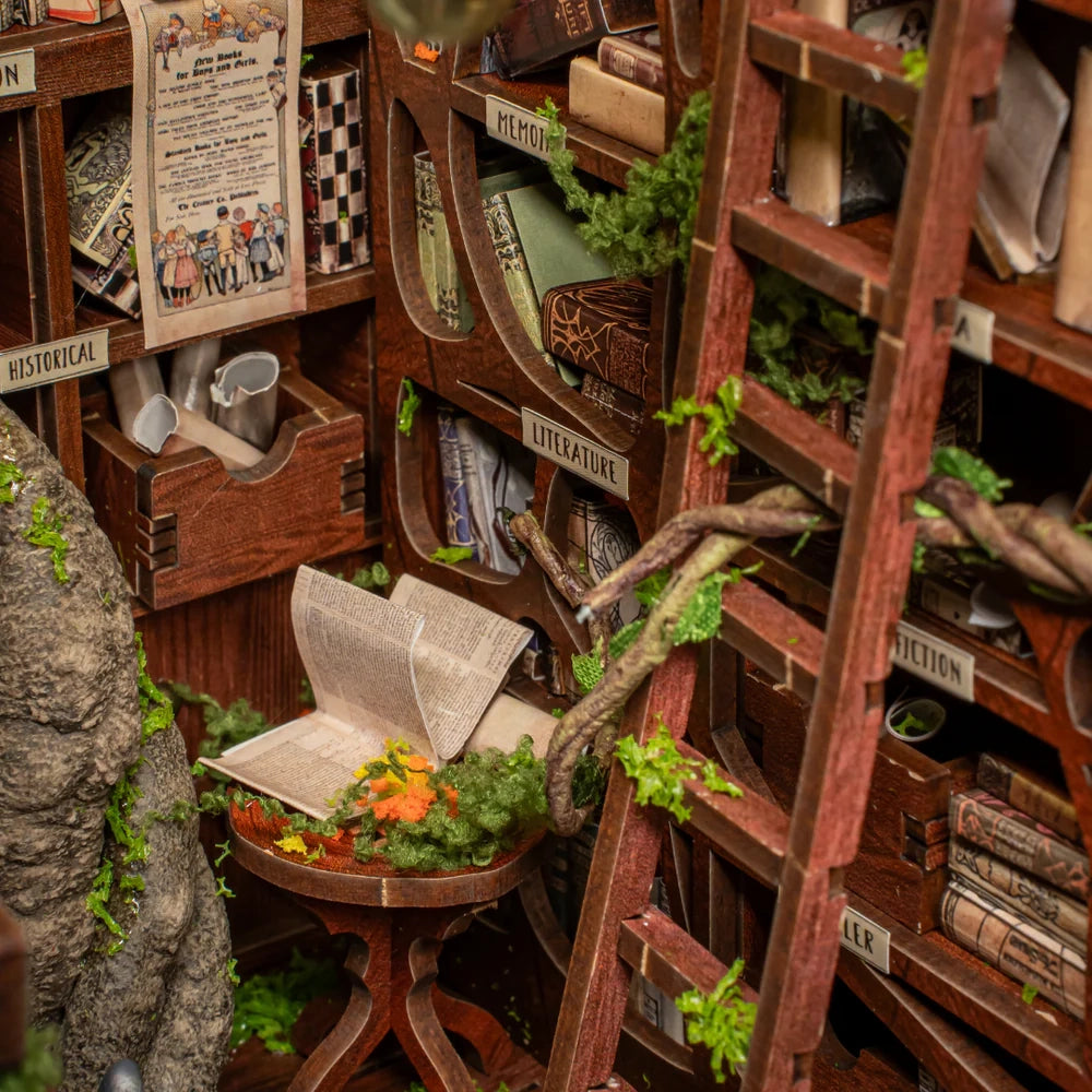 Miniatur-Bücherregal mit Leiter und offenem Buch auf einem Tisch