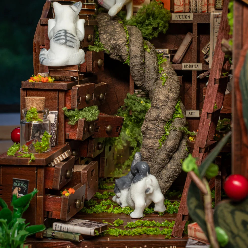 Miniatur-Bücherregal mit Katzenfiguren und Pflanzen