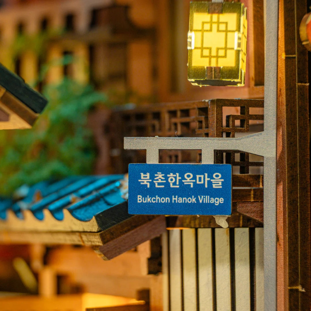 Miniaturmodell eines Straßenschildes mit der Aufschrift Bukchon Hanok Village und einer beleuchteten Laterne