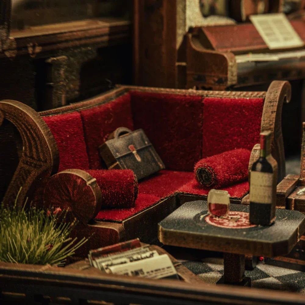 Miniatur-Wohnzimmer mit rotem Sofa, Aktentasche, Weinflasche und Glas auf einem Tisch