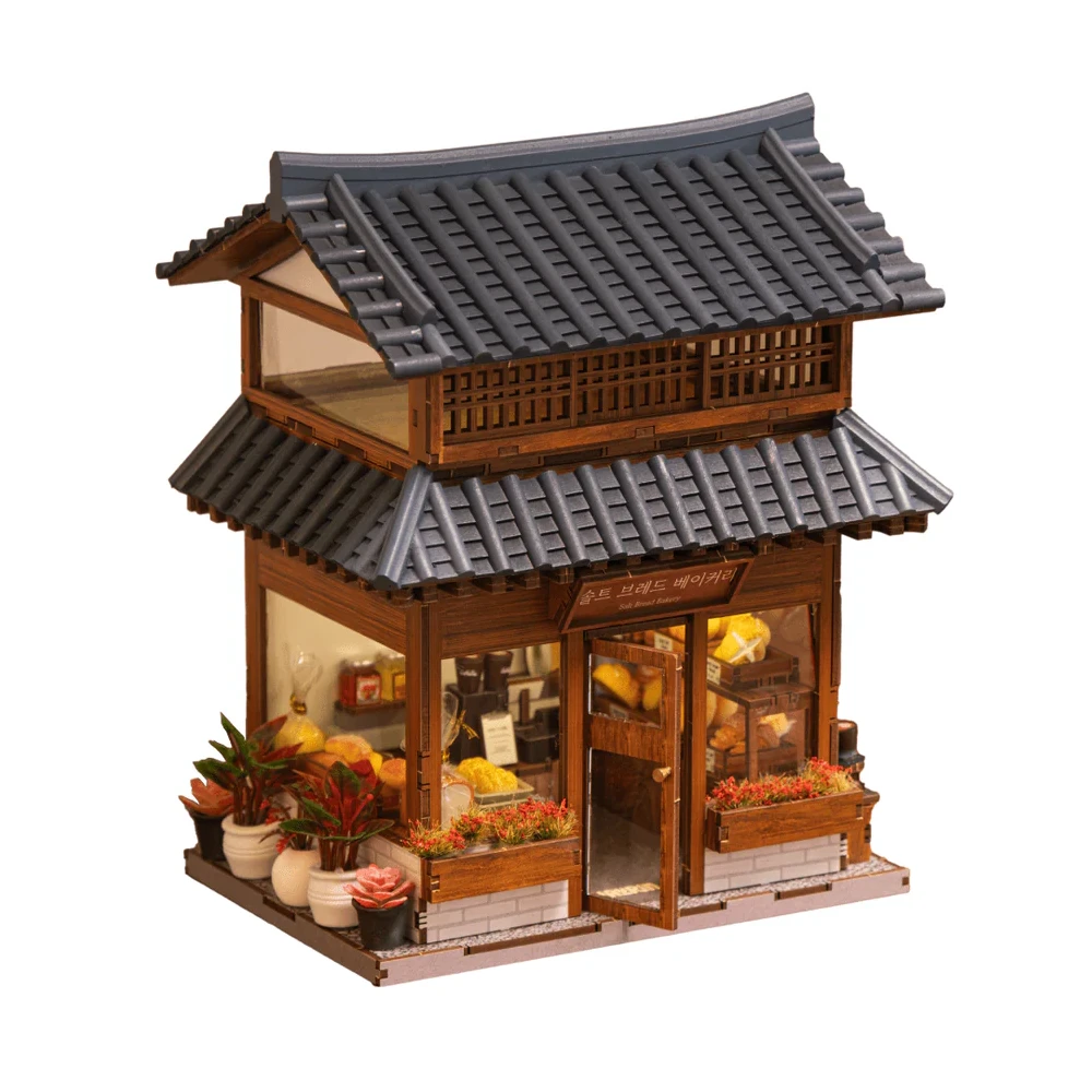 Miniatur-Bäckerei mit Holzfassade, grauen Ziegeldächern und Pflanzen vor dem Eingang