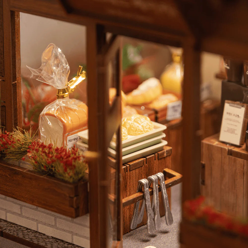 Miniatur-Bäckerei mit Brot, Gebäck und Zangen in einem Holzregal