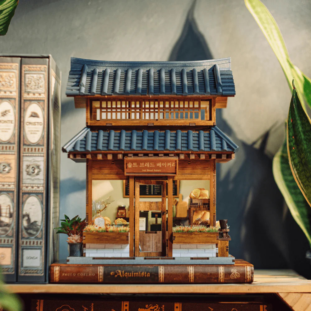 Miniatur-Bäckerei-Modell auf einem Buch mit blauen Ziegeldächern und Holzwänden