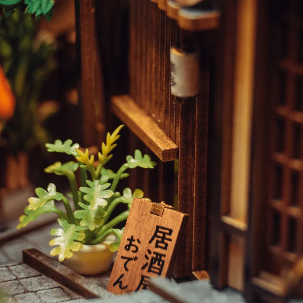 Miniatur-Pflanze in Topf vor Holzwand mit japanischem Schild