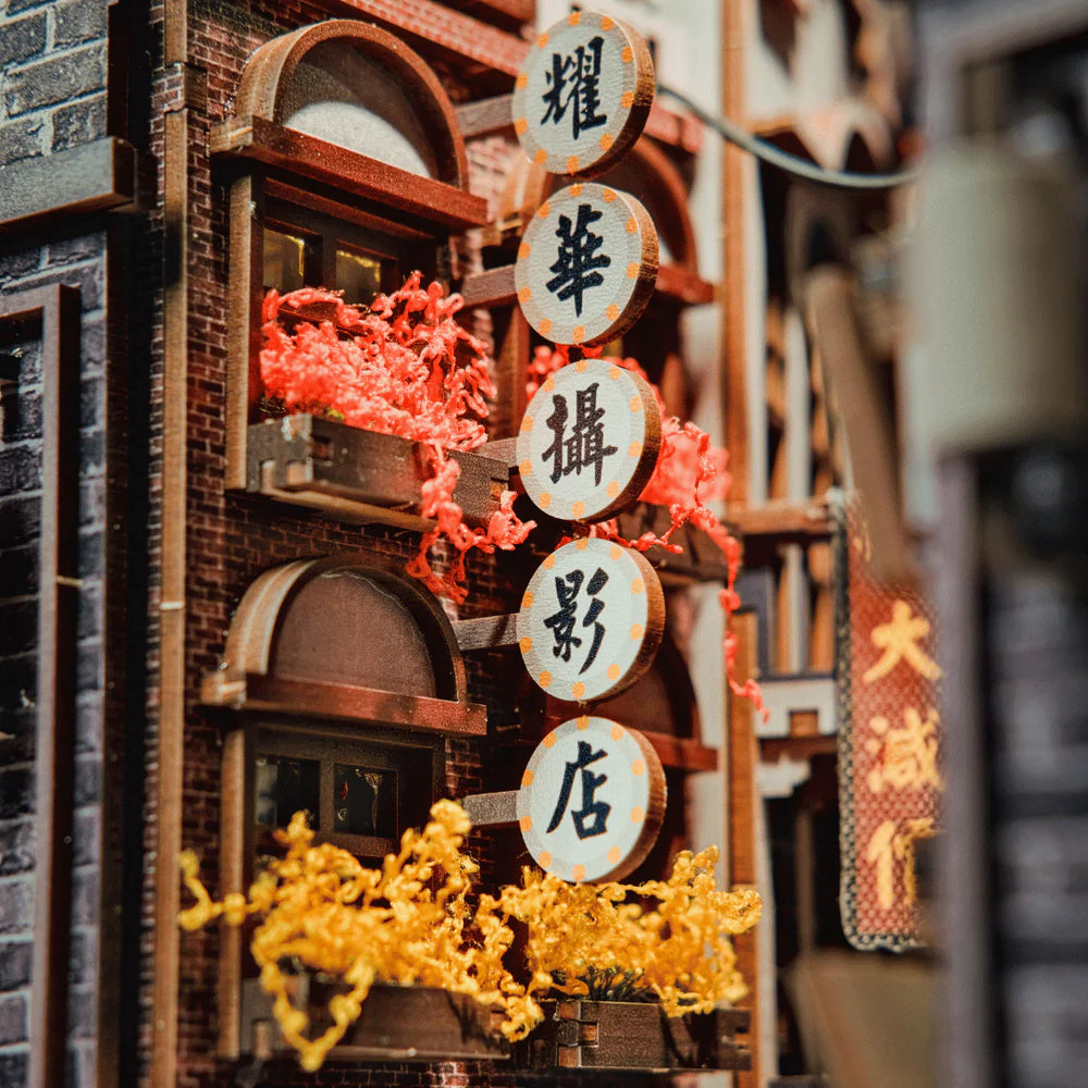 Miniaturgebäude mit roten und gelben Pflanzen in Blumenkästen und runden Schildern mit chinesischen Schriftzeichen