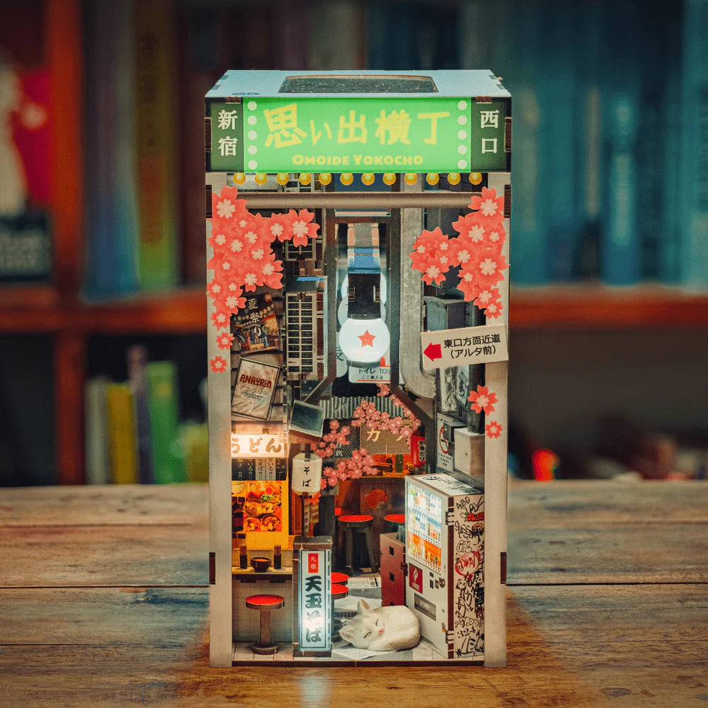 Miniatur-Diorama einer japanischen Gasse mit Geschäften, Laternen, Kirschblüten und einer schlafenden Katze