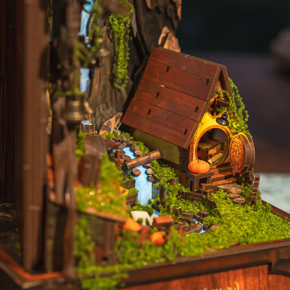 Miniatur-Hobbit-Haus mit rundem Eingang, Holzfassade, Moos, Fluss und Kürbis