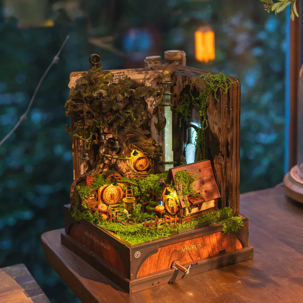 Diorama eines Hobbit-Hauses mit leuchtenden Fenstern und üppigem Grün