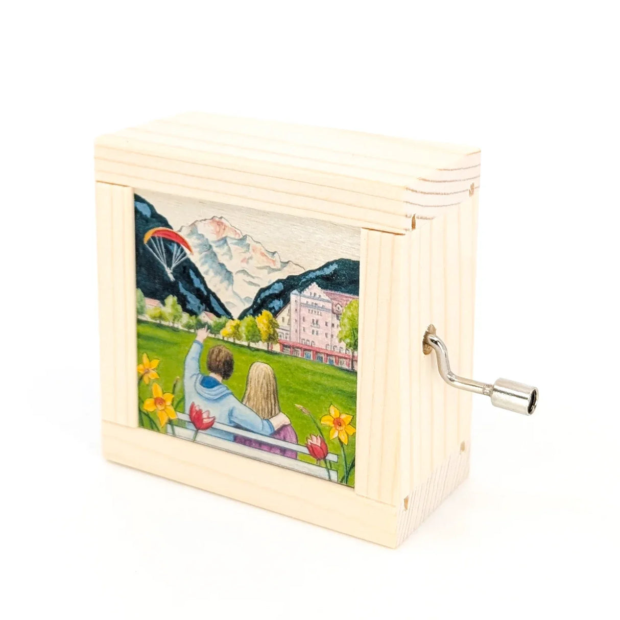 Holzspieldose mit Paar auf Bank, Blick auf Berge, Hotel und Gleitschirmflieger