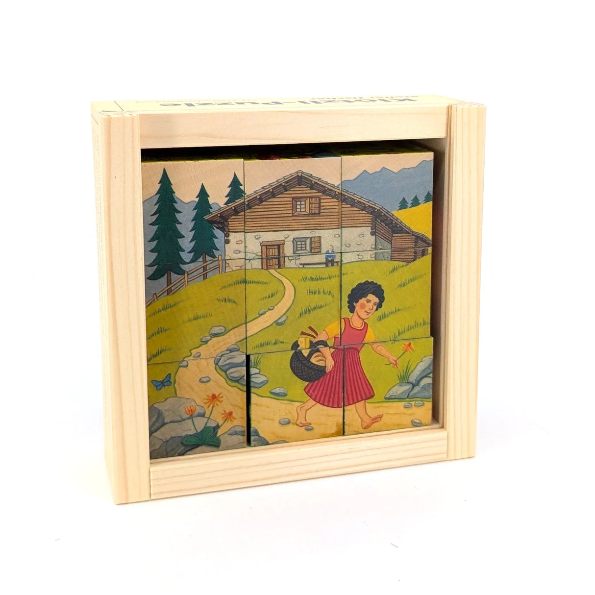 Heidi-Puzzle in Holzkiste mit Heidi auf einem Pfad vor einem Haus in den Bergen