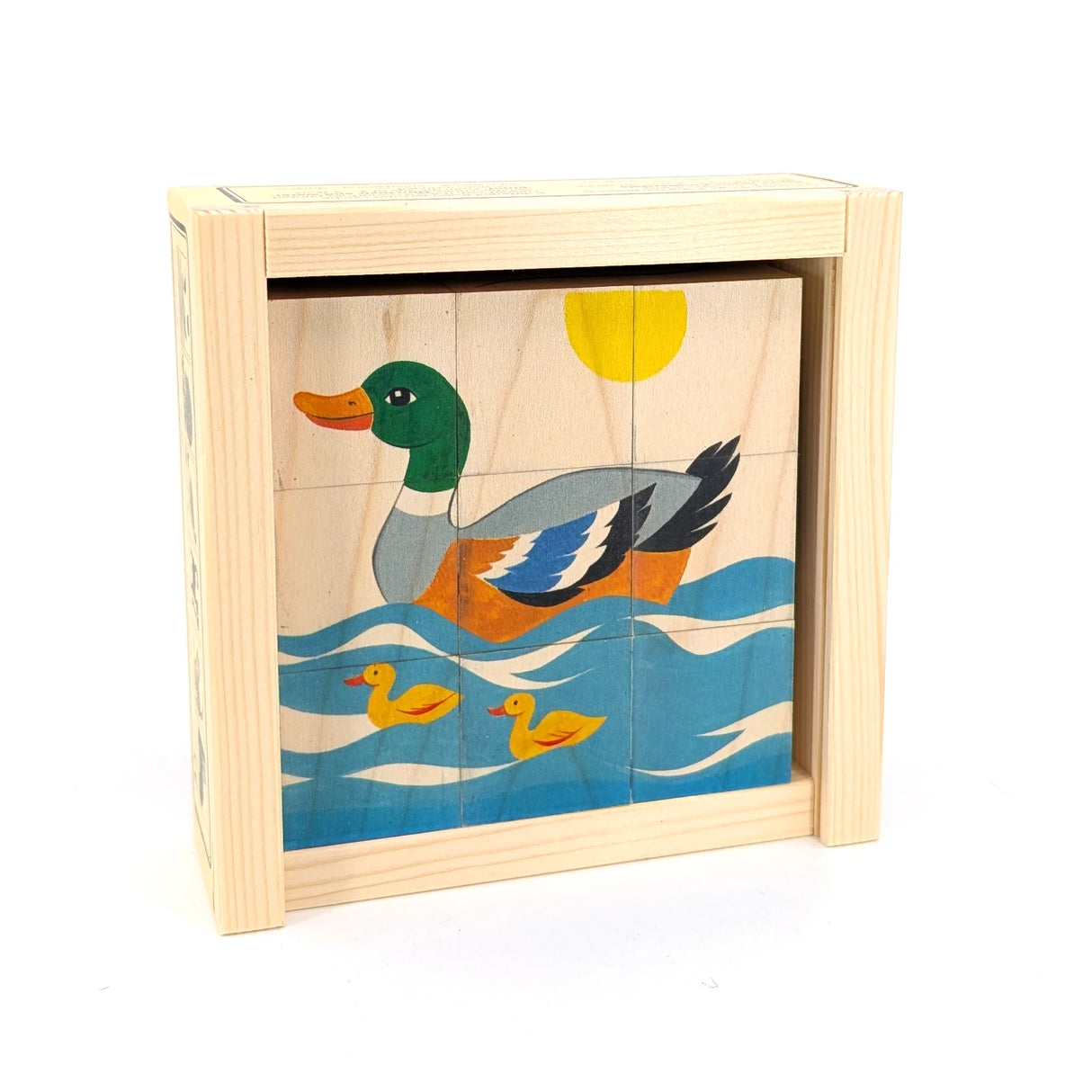 Holzpuzzle mit einer Ente und zwei Küken auf blauem Wasser unter einer gelben Sonne