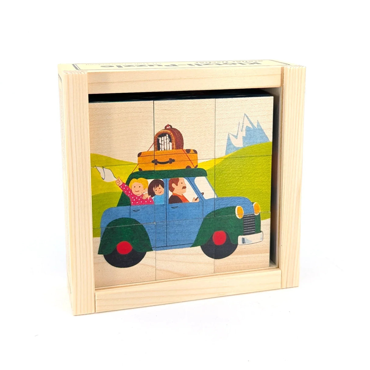 Holzpuzzle mit einem blauen Auto, das eine Familie und Gepäck transportiert, vor einer Berglandschaft