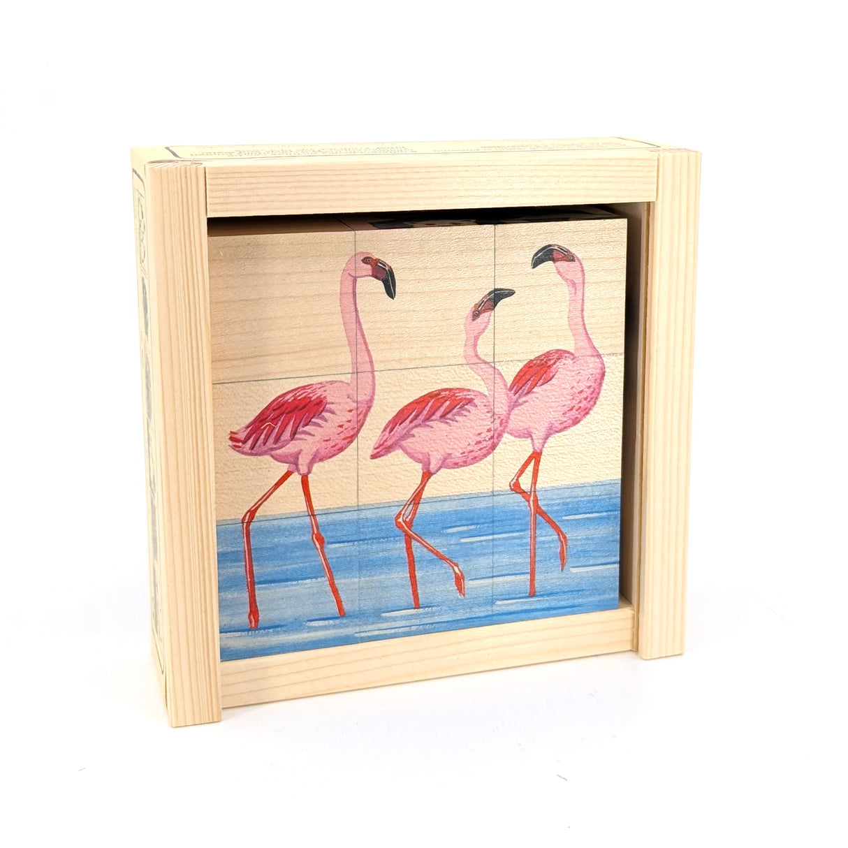 Drei rosa Flamingos stehen in blauem Wasser, dargestellt auf einem Holzpuzzle in einem Holzrahmen