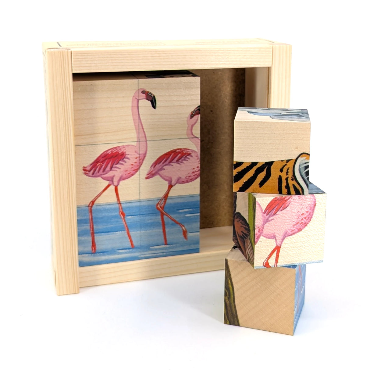 Holzrahmen mit zwei Flamingos in blauem Wasser, daneben gestapelte Würfel mit Tiermotiven