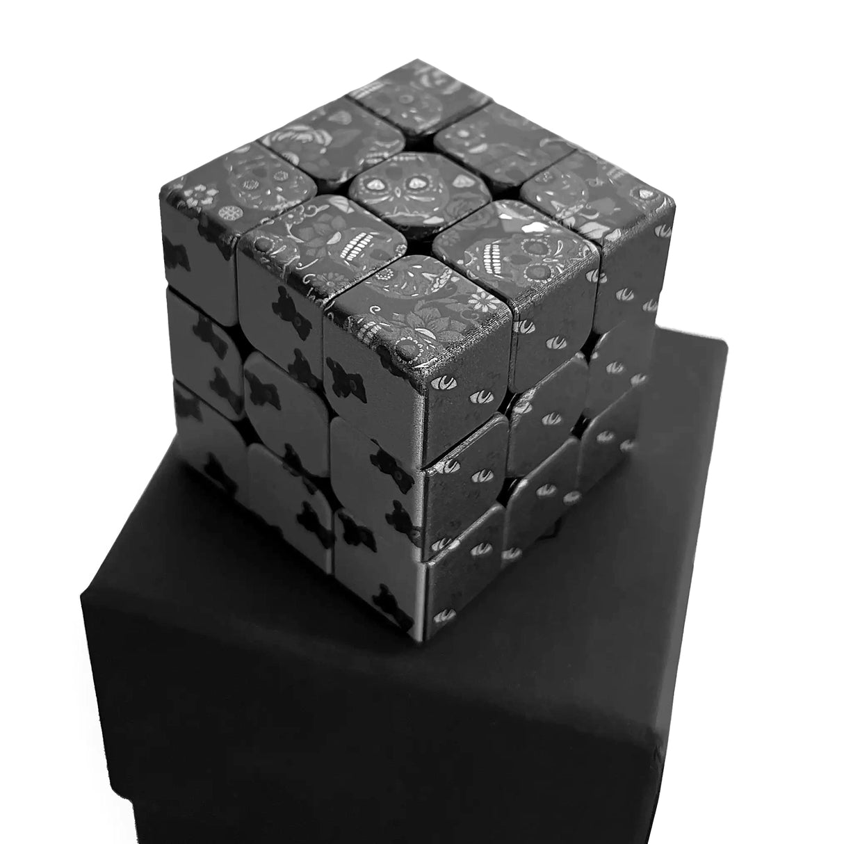 Rubikswürfel mit Totenkopf- und Blumenmuster auf schwarzem Sockel