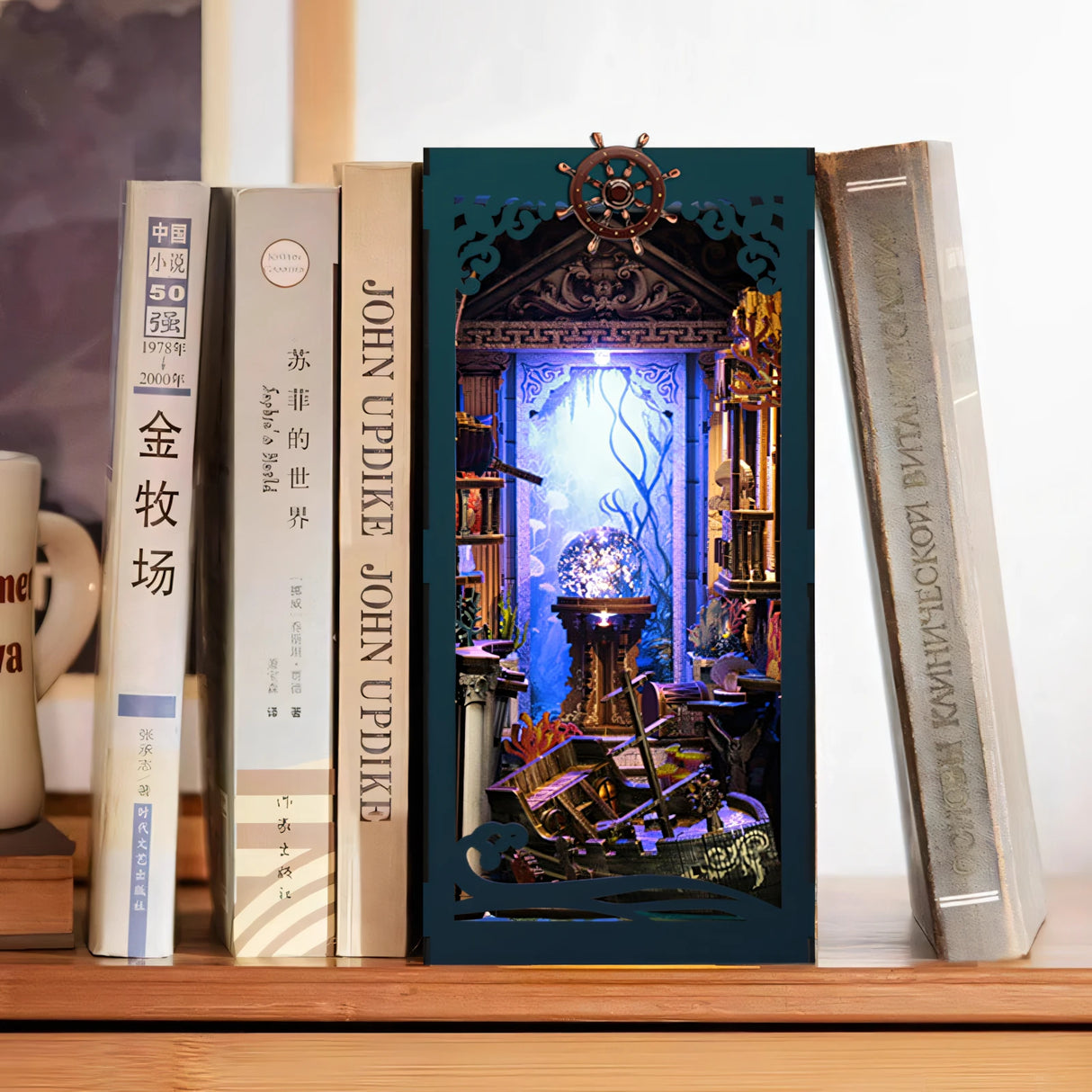 Ein Bücherregal-Einsatz mit einem Unterwasser-Diorama, das ein Schiffswrack und leuchtende Korallen zeigt