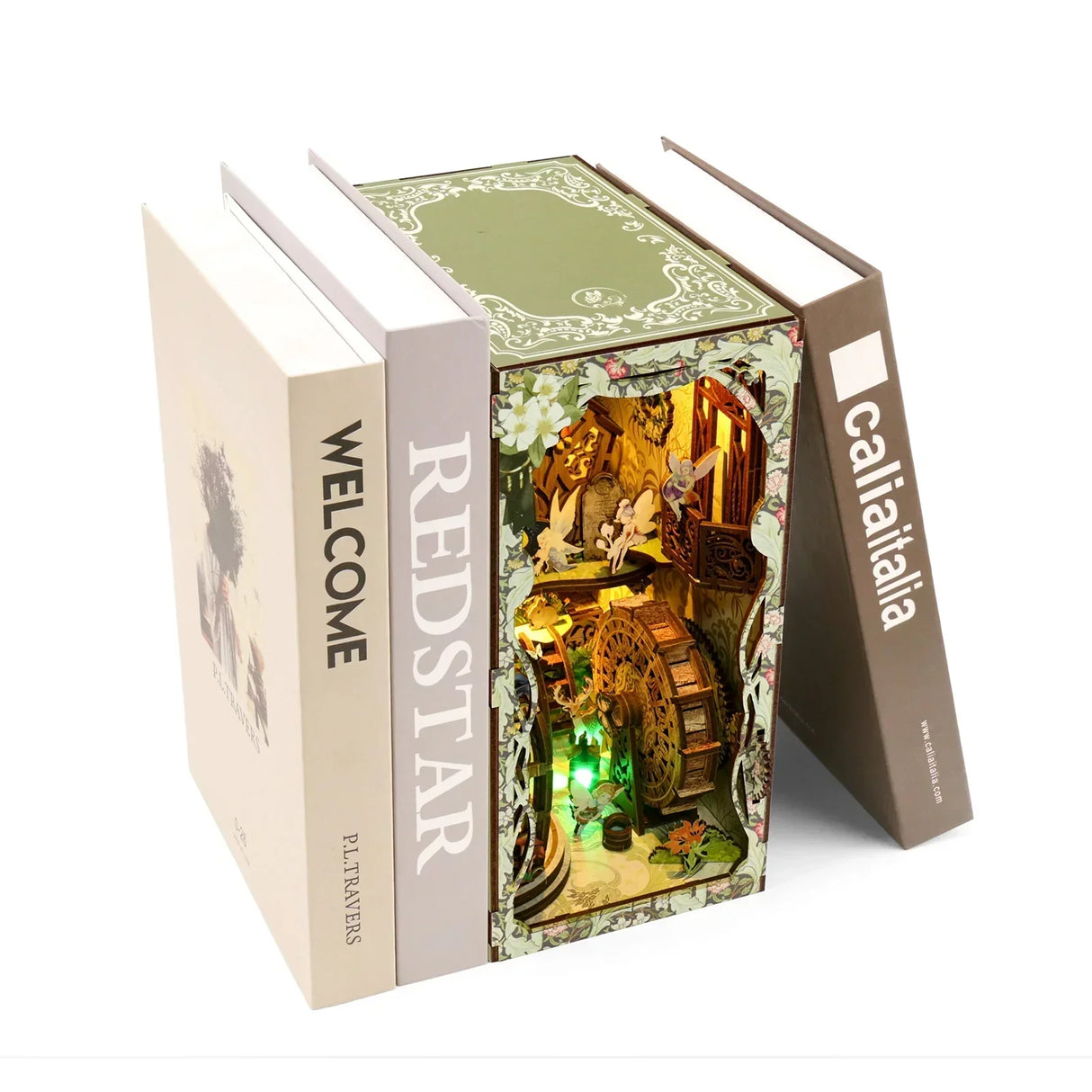 Drei Bücher, das mittlere ist ein beleuchtetes Diorama mit Feen und einem Wasserrad