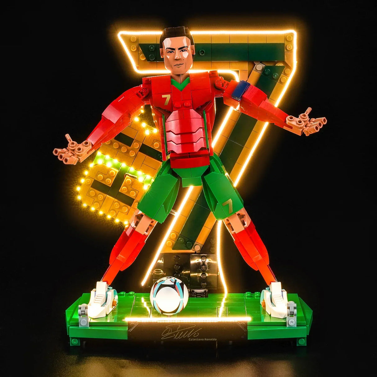 Schräge Gesamtansicht der LEGO Cristiano Ronaldo Figur in der „Siu“-Pose auf einem grünen Podest mit eingeschalteter BrickBling LED-Beleuchtung vor schwarzem Hintergrund.