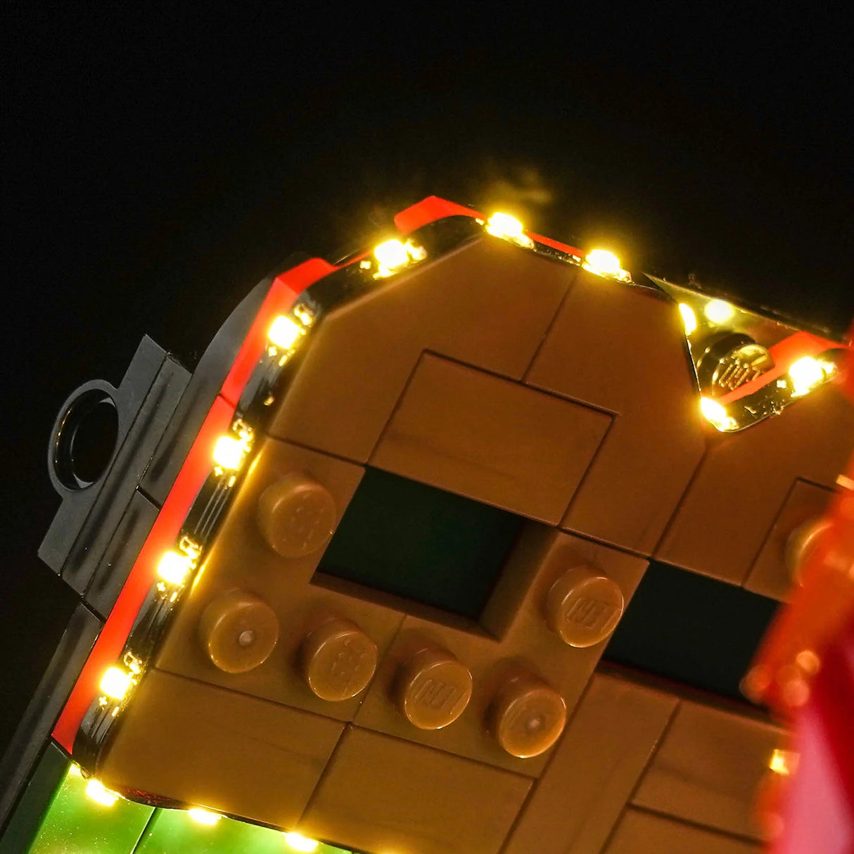 Detailansicht einer LEGO-Rückwand aus braunen und roten Steinen, die entlang der Kanten mit einer hellen, warmen LED-Lichterkette von BrickBling beleuchtet wird.