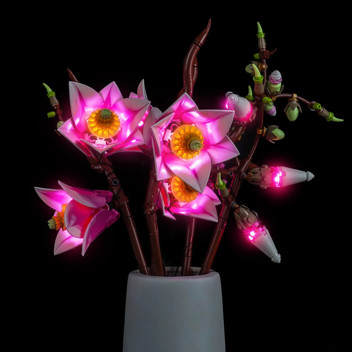 Nahaufnahme der LEGO Magnolienzweige in einer Vase mit leuchtend pinken Blütenköpfen und strahlenden Knospen.
