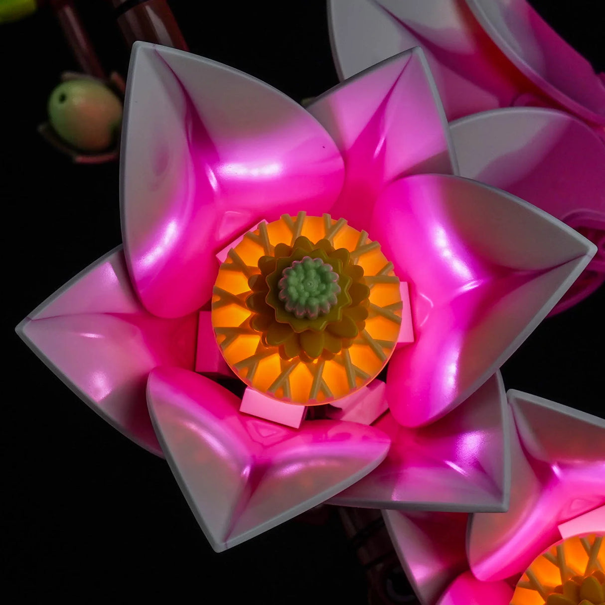 Makroansicht einer geöffneten LEGO Magnolienblüte von oben, beleuchtet durch gelbe und pinke LEDs von BrickBling.