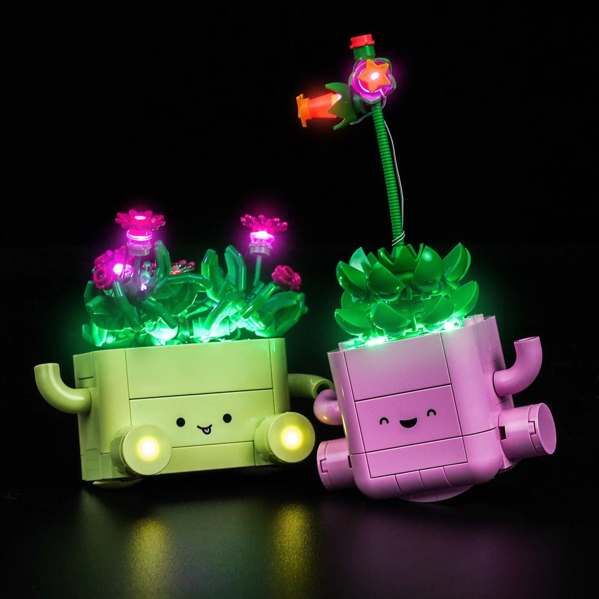 Zwei beleuchtete LEGO-Pflanzen in einem grünen und einem rosa Topf mit Armen, ausgestattet mit LED-Beleuchtung von BrickBling.