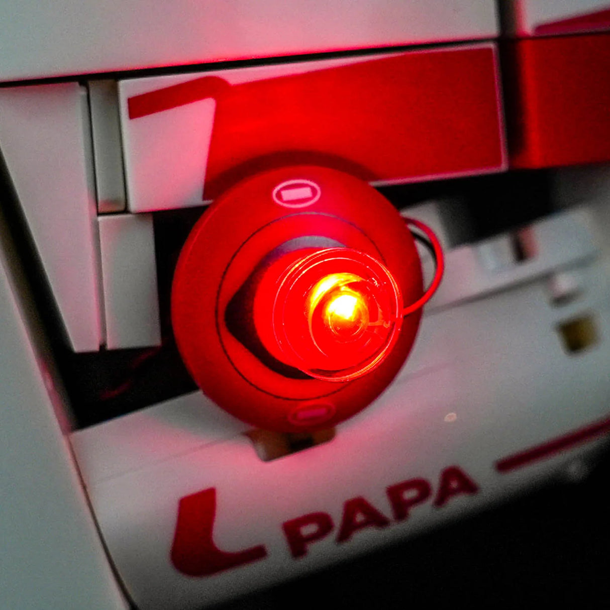 Nahaufnahme eines roten BrickBling LED-Lichts, das an der Seite des LEGO Scuderia Ferrari Charles Leclerc Helms montiert ist und hell leuchtet.