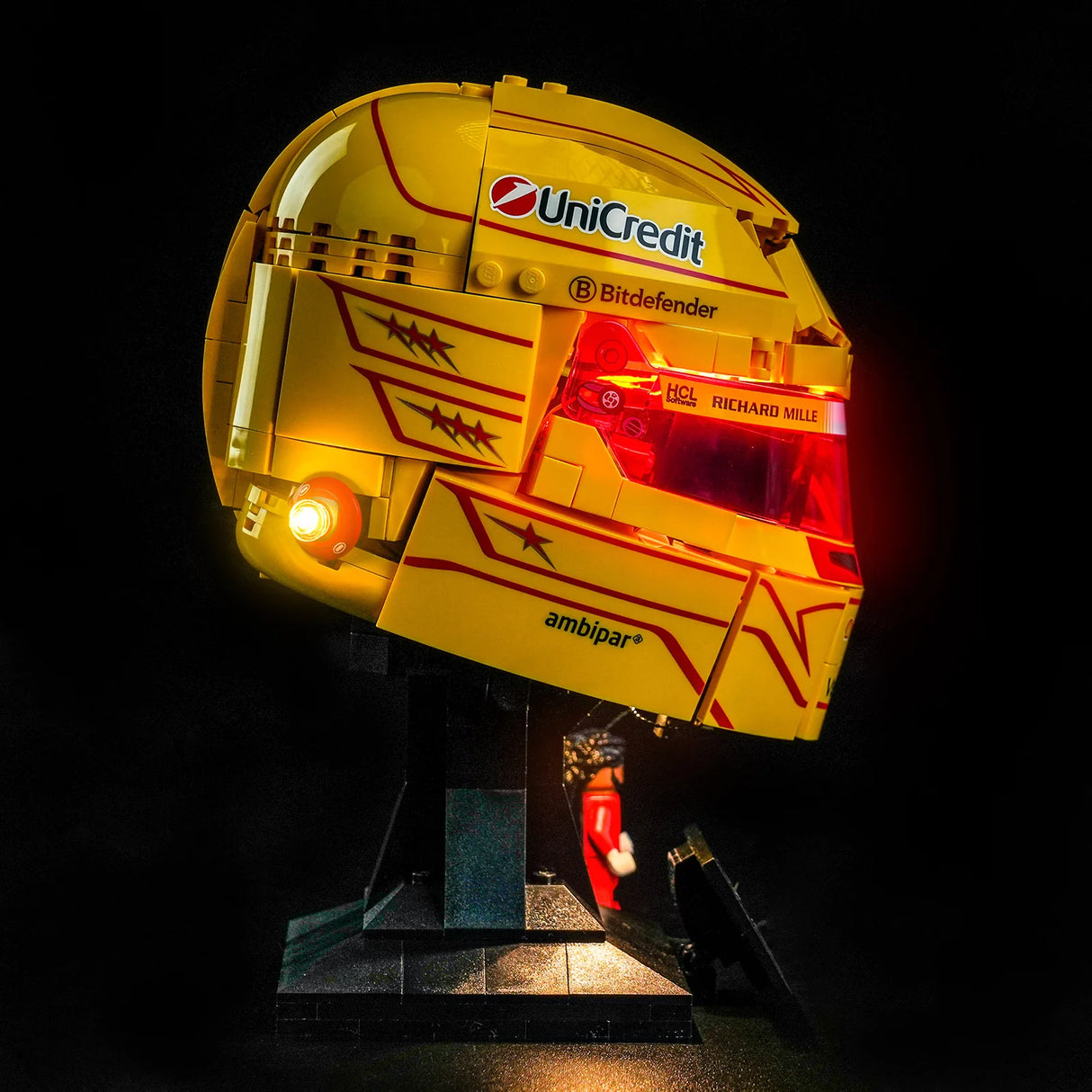 Seitenansicht des LEGO Lewis Hamilton Helms mit aktivierter BrickBling LED-Beleuchtung, UniCredit-Sponsorenlogo und rot illuminiertem Visier auf schwarzem Hintergrund.