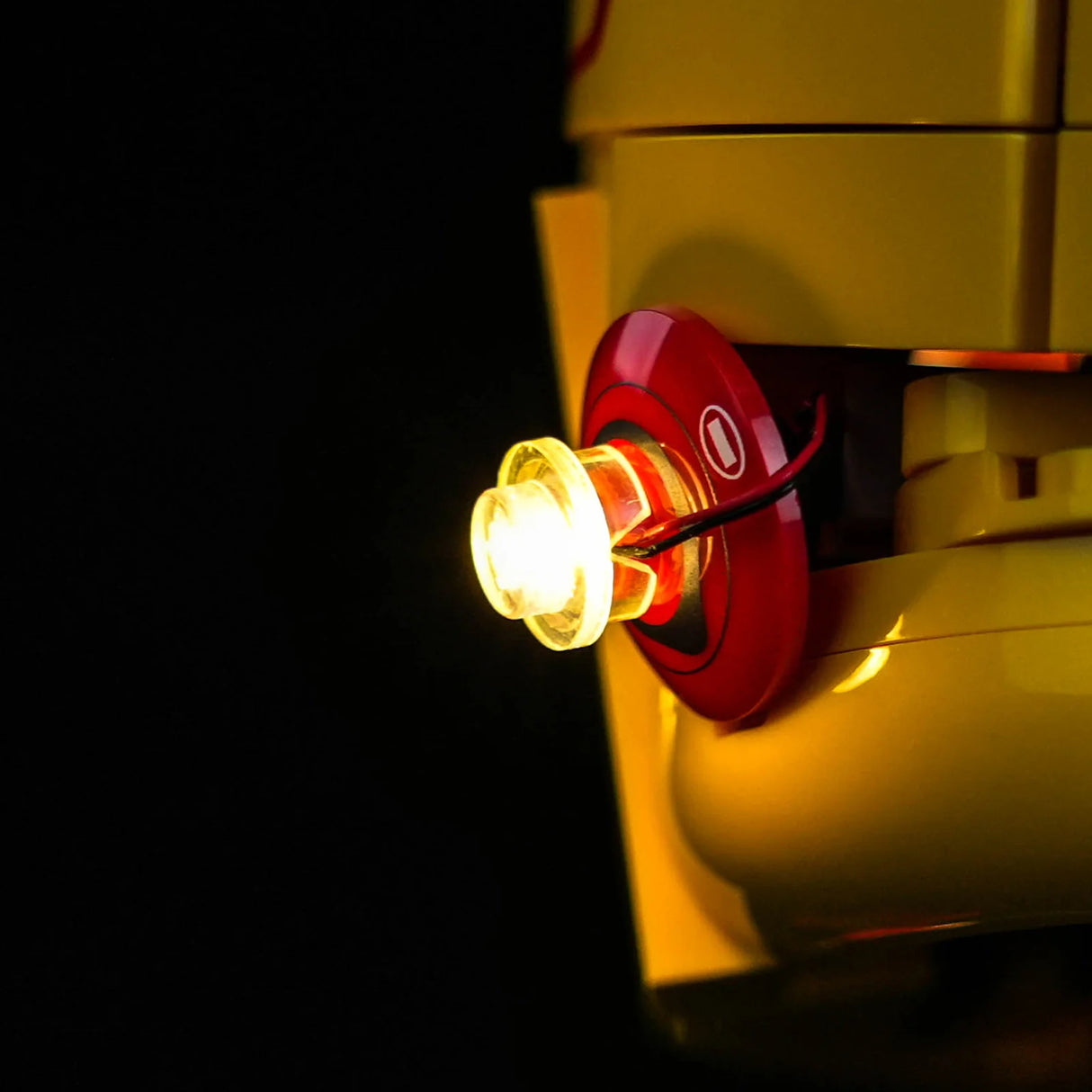 Nahaufnahme der seitlichen LED-Beleuchtung von BrickBling für den LEGO Scuderia Ferrari HP Lewis Hamilton Helm mit filigraner Kabelführung an einem roten LEGO-Teil.