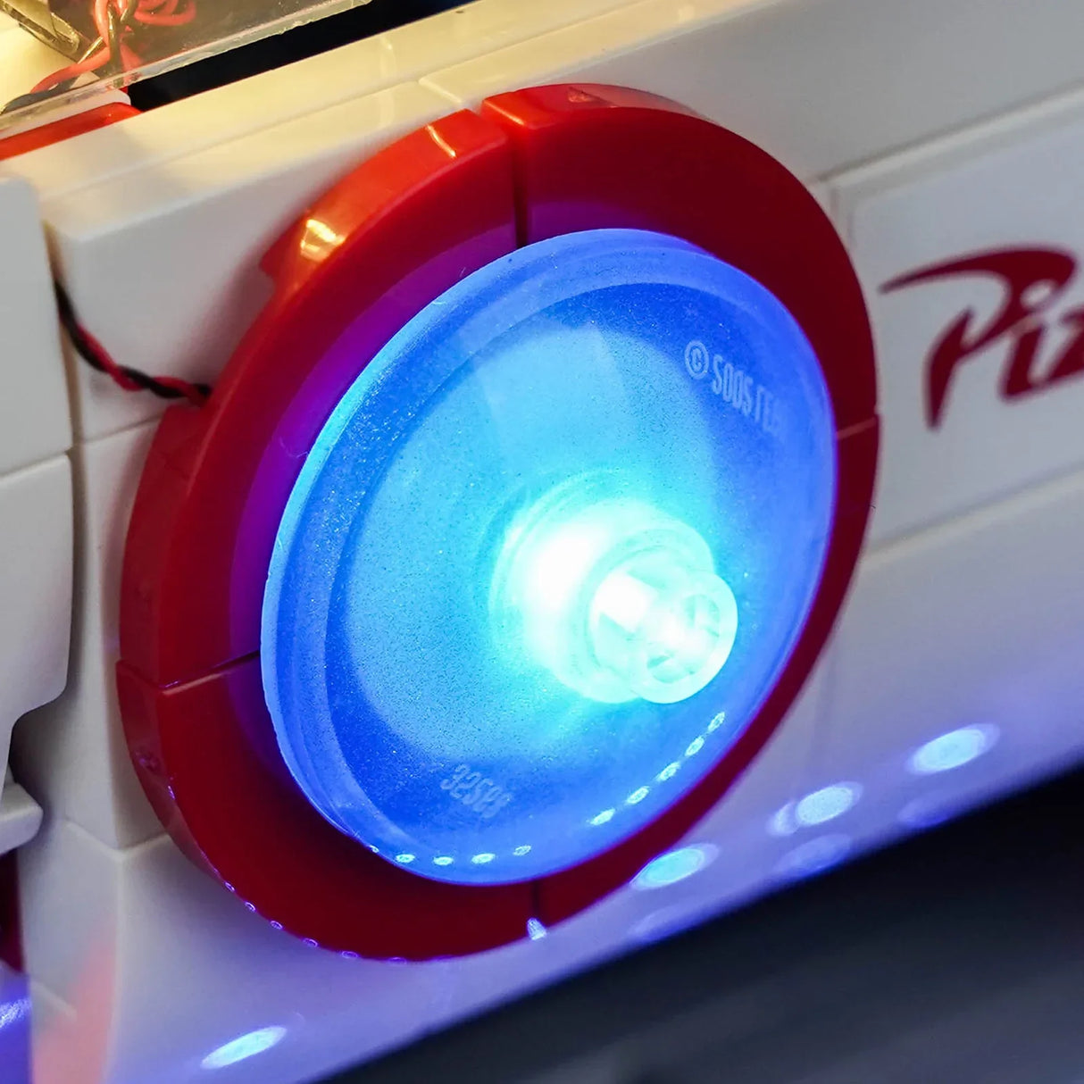 Detailaufnahme des blau leuchtenden runden LED-Elements an der Seite der LEGO Pizza Planet Rakete von BrickBling.