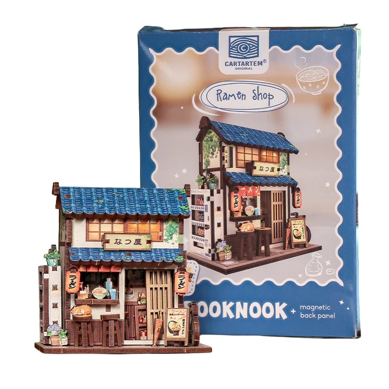 Miniatur-Ramen-Laden-Modell mit blauen Dachziegeln und Laternen, daneben die Verpackung