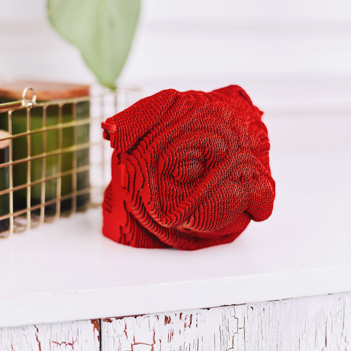 Rote Mops Skulptur aus geschichteten Kartonlamellen auf einem weißen Tisch