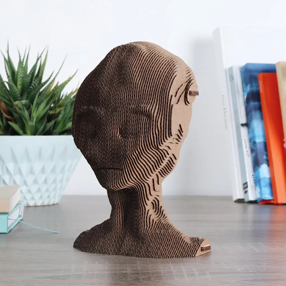 Skulptur eines menschlichen Kopfes aus geschichtetem Wellpappe auf einem Schreibtisch